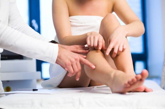 doctor examines legs for varicose veins